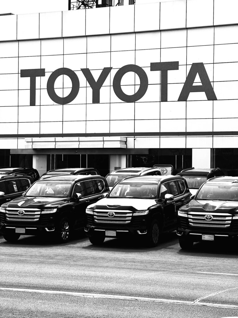 Black and white photo of Toyota SUVs parked at a dealership in an urban setting in Tianjin, China.