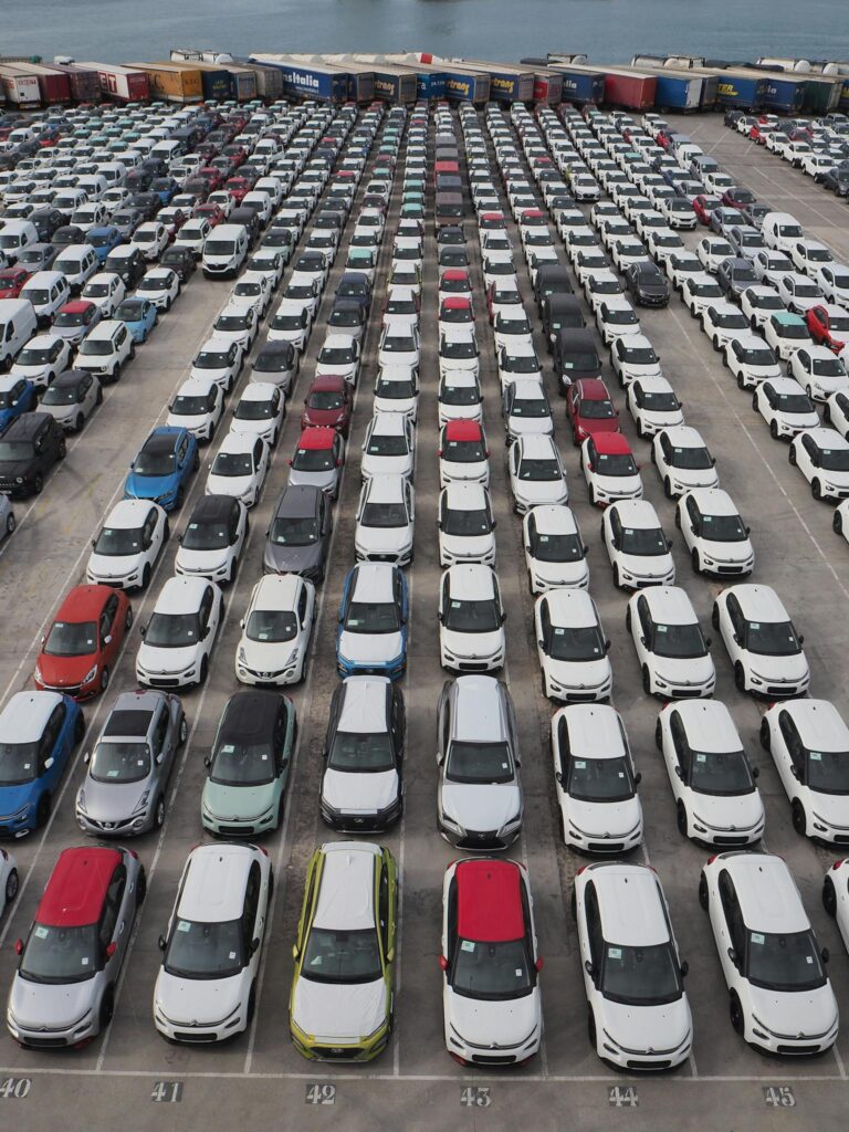 Top-down view of a large parking lot with rows of cars in Barcelona's port area.